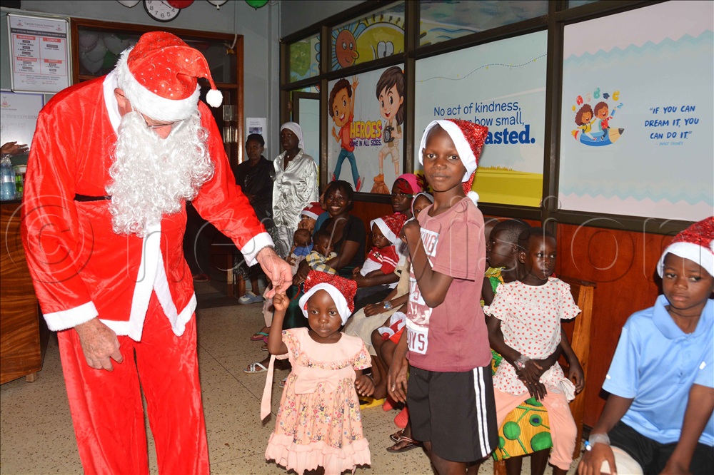 Father Christmas David Sanders (left)  interacts with children admitted at Uganda Cancer Institute ward during a Christmas party in Kampala. 
