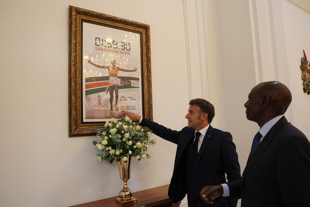 France's President Emmanuel Macron (2nd R) points to a frame photograph of Kenyan marathon runner Sabastian Sawe, crossing the finish line to win the London Marathon after breaking a historic world record, next to Kenyan President William Ruto (1st R) during a reception at State House ahead of the Africa Forward: Africa- France Partnerships for Innovation and Growth Summit in Nairobi, on May 10, 2026. 