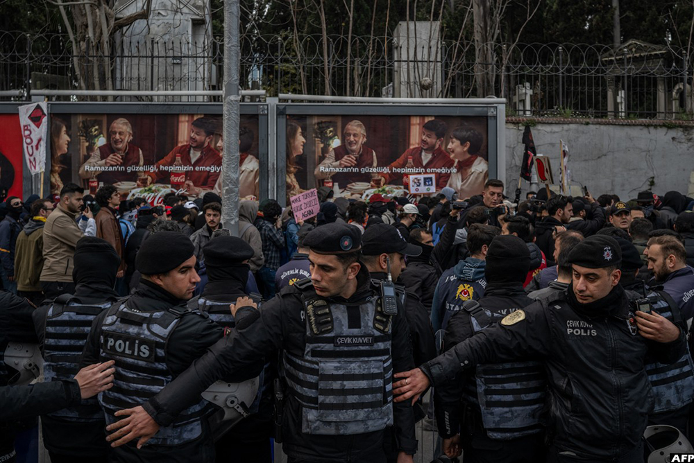 Turkish anti-riot police officers stand guard as students take part in a rally in support of the city's arrested mayor