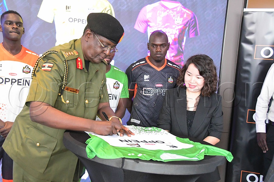 Lt. General James Mugira signs the NEC FC jersey during the launch of the NEC–OPPEIN sponsorship deal on October 6 at the CHINT building along Jinja Road, as OPPEIN Managing Director Sherry Shi (Namutebi) looks on. Photo: Silvano Kibuuka