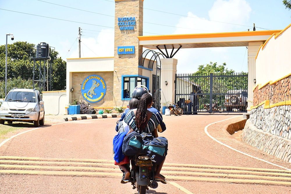 A parent arriving on a boda boda with her child at Busoga College Mwiri. (Photo by Donald Kiirya)