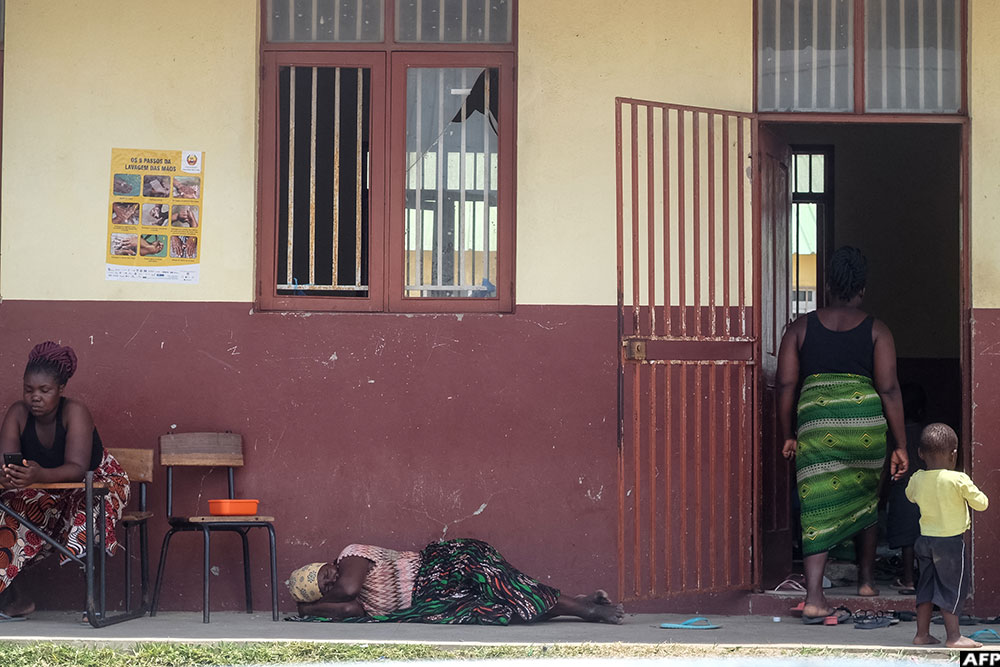 A displaced person sleeps as others enter a door at an emergency shelter in the town of 3 De Fevereiro. (AFP)