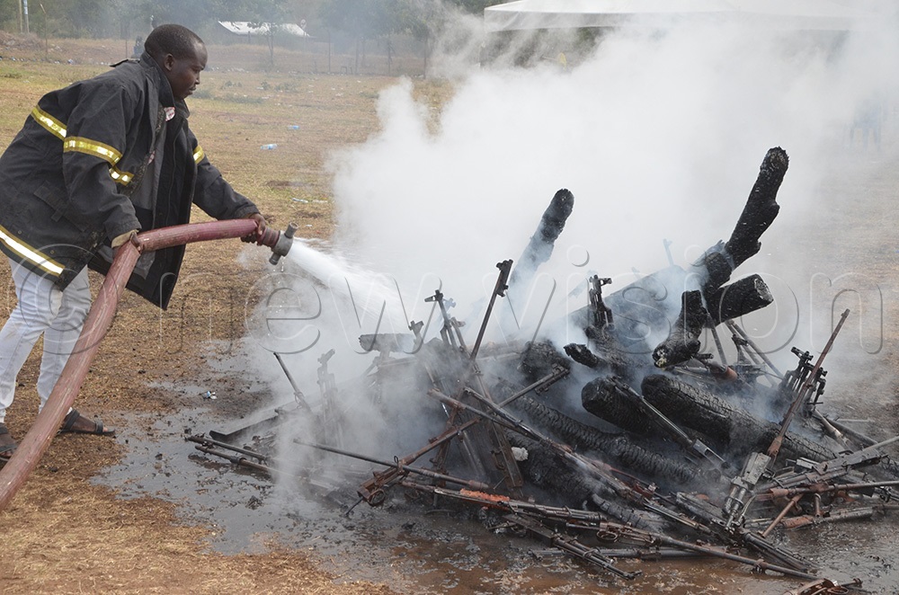 Unidentified fire fighter puts out the fire after the guns were burnt at Naitakwae in Moroto. (Photo by Olandason Wanyama)