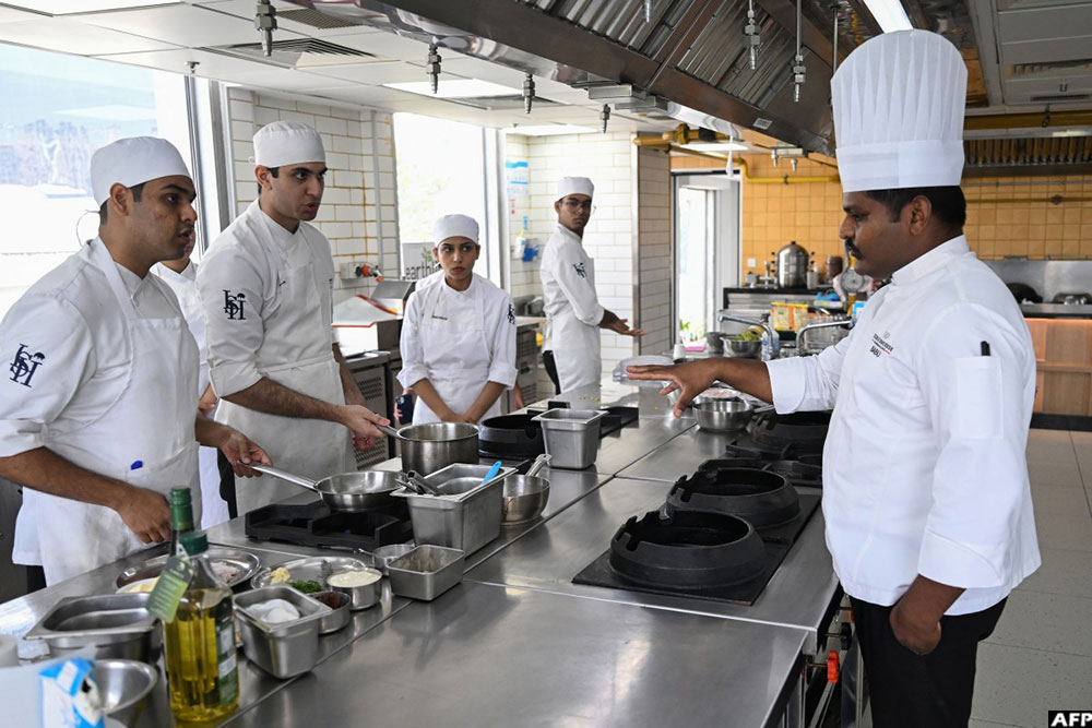 A culinary chef interacting with students inside a kitchen at the &Eacute;cole Ducasse.