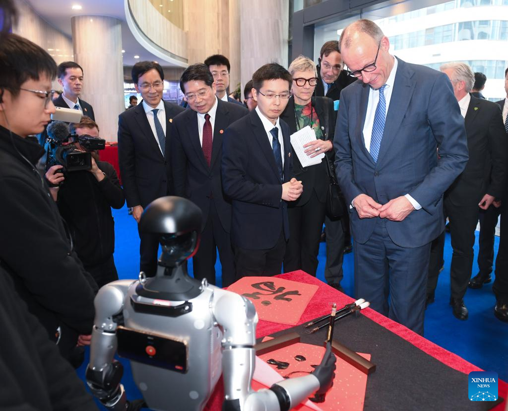German Chancellor Friedrich Merz, who is on an official visit to China, watches a humanoid robot of Unitree Robotics writing the Chinese character "Fu", meaning "good fortune", in Hangzhou, east China's Zhejiang Province, Feb. 26, 2026. (Xinhua Photo)