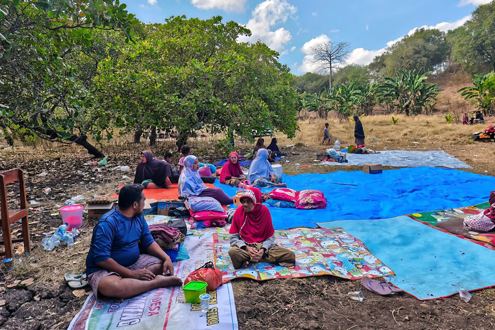 Villagers look on after spending the night in an open field in Nangahale village in Sikka, East Nusa Tenggara, on August 16, 2026, after a magnitude 7.7 earthquake off Indonesia's eastern Flores island. (Photo by ARNOLD WELIANTO / AFP)