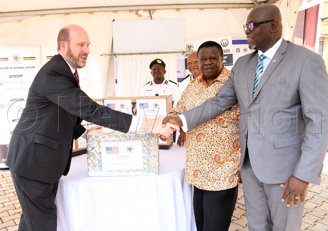 The US Ambassador to Uganda, William W. Popp shaking hands with Sanusi Tejan Savage, Chief of Mission of the International Organisation for Migration (IOM) in Uganda, as Minister for Internal Affairs Maj. Gen. Kahinda Otafiire looks on.