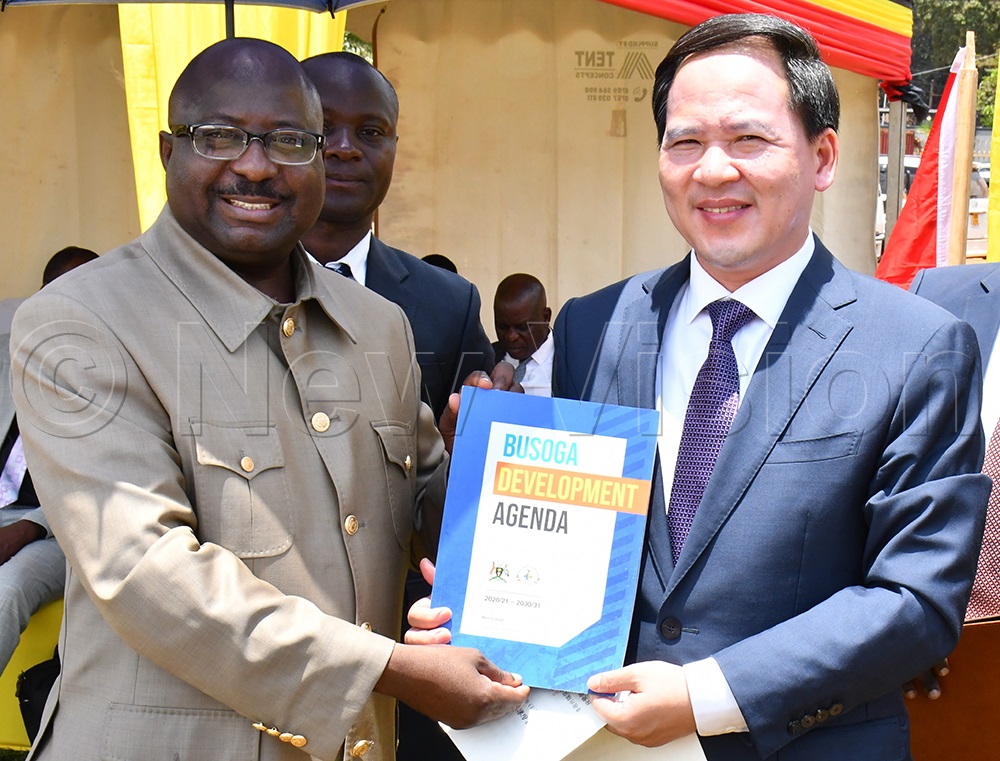 BCD's Governor Bishop Frank Tibagendeka (left) handing over a copy of the Busoga Development Agenda to the Shandong Province Vice Governor Wen Nuan (right) while at the signing ceremony for the establishment of cooperation between BCD and Shandong Province at the Civil Service College of Uganda, Jinja City on Monday. (Photo by Donald Kiirya)