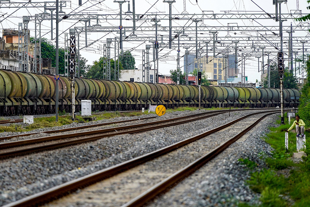  A man sits by railway tracks as a freight train transports petrol wagons in Ajmer on August 27, 2025. US tariffs of 50 percent took effect on August 27, on many Indian products, doubling an existing duty as President Donald Trump sought to punish New Delhi for buying Russian oil. 