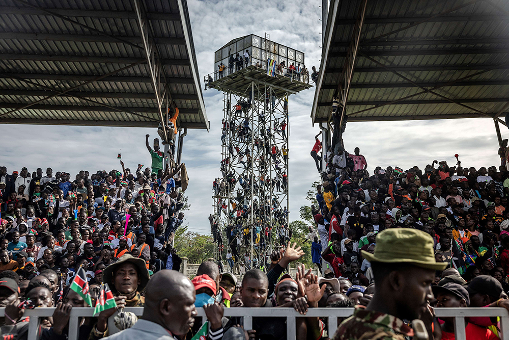 Mourners and supporters of Kenya’s opposition leader and former Prime Minister Raila Odinga climb on top of a structure outside the stadium following the arrival of his coffin to his home region in Kisumu, on October 18, 2025. (AFP)
