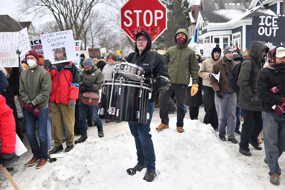 A protester holds drums as they march from Powderhorn Park in Minneapolis against Immigration and Customs Enforcement (ICE) and the fatal shooting of Renee Good by an ICE agent, calling on federal authorities to leave the city and demand accountability, in Minneapolis, Minnesota, on January 10, 2026. (Credit: AFP)