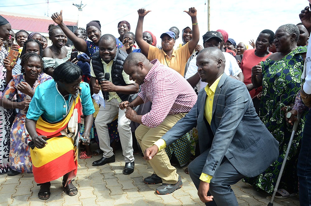 Balaam Barugahara (checked shirt), the minister of state for youth and children affairs dancing with the mayor of Ayivu division Arua city Marlon Avutia and other vendors of the new Carnegie A1 Community Market in Ayivu division Arua City. This was during his courtesy visit to the market during his Youth Wake Up Call Mobilisation and Accountability Tour in Arua City on October 13, 2025. (Credit: Lawrence Mulondo)