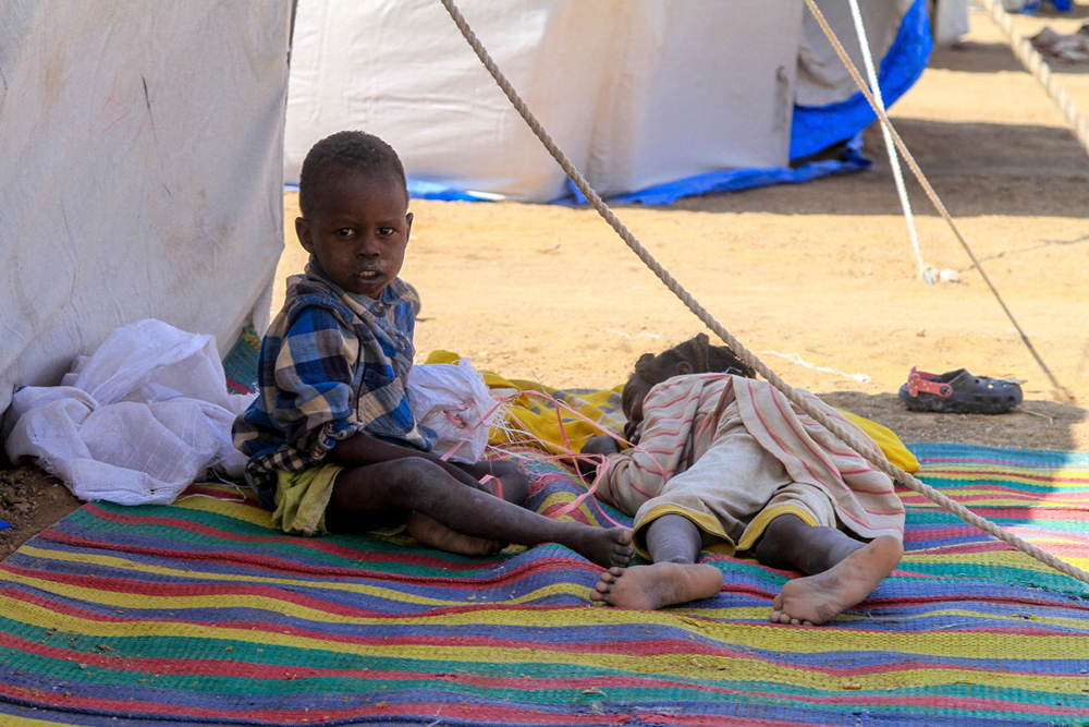 Children from El-Fasher rest outside their tent at a camp for displaced Sudanese people in the northern town of Al-Dabba on November 13, 2025. 