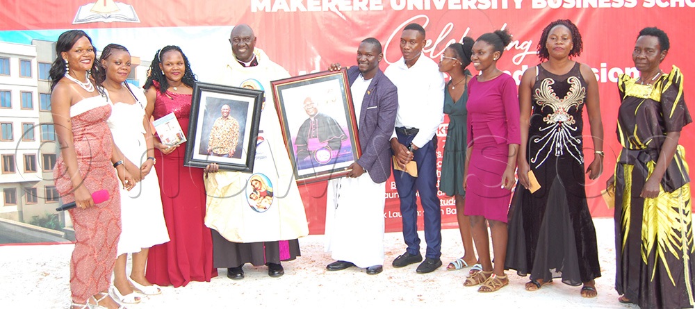  Msgr. Dr. Laarry Ssemusu (wearing a black cassock) is joined by Fr. Joseph Kirumira (left) and some members of the Pastoral Council of St. Charles Lwanga Catholic Community, MUBS, as he cuts cake in celebration of his 45th priestly anniversary and 70th birthday at MUBS on Saturday, October 4, 2025. (Photo by Mathias Mazinga)