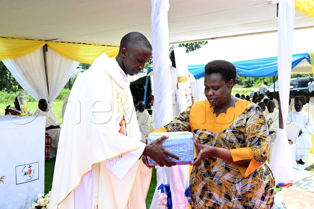 Vice President Jessica Alupo handing over a gift to the newly ordained priest Olupot. (Credit by Delux Emmy Alomu)