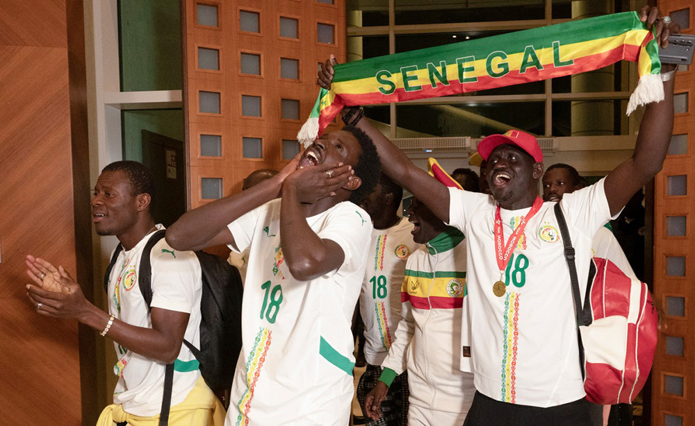 Senegalese supporters who were granted a royal pardon in Morocco cheer as they arrive at Blaise Diagne International Airport in Ndiass, Senegal on May 24, 2026, after being held in Morocco since the Africa Cup of Nations final. (Photo by SEYLLOU / AFP)