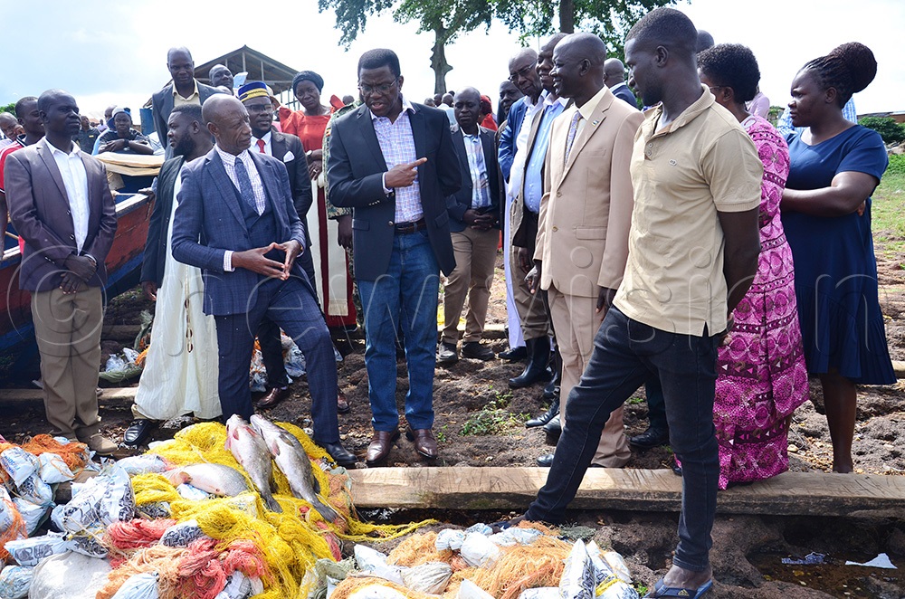 Katikkiro of Buganda Charles Peter Mayinga chating with  Michael Mbowa Wamala, the Buvuuma sub-county chief (left) and other officials at Kasaali B landing site. (Photo by Agnes Kyotalengerire)