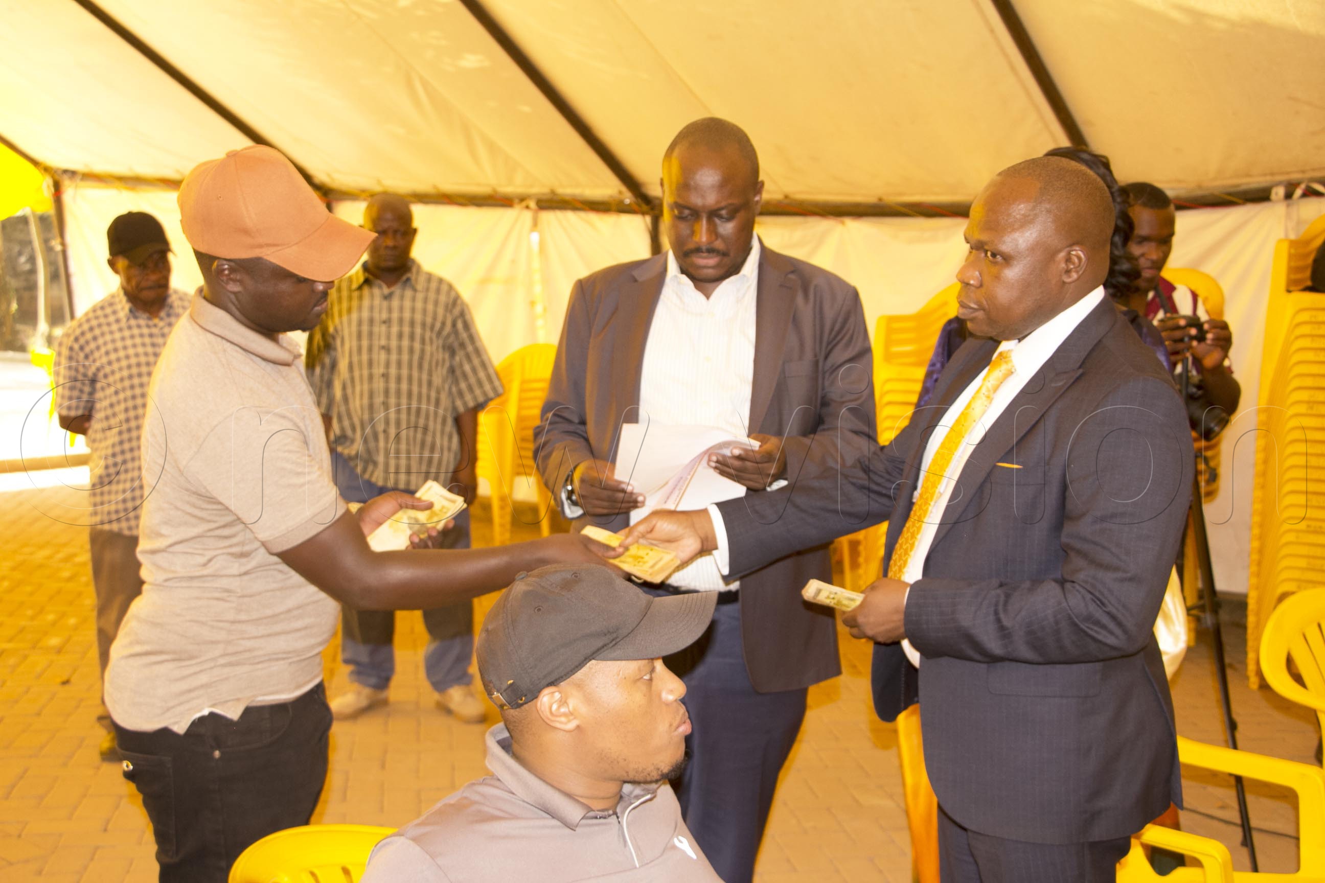 The PLU leaning candidate Daniel Izale counting sh3m nomination fees to contest as NRM candidate for Adjumani West constituency with PLU supporters assisting him in the process at NRM electoral commission Kyadondo Road in Kampala (Photo by Isaac Nuwagaba)