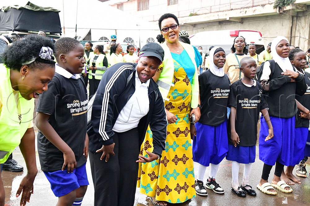 Dr. Joyce Kaducu Moriku, Minister of State for Primary Education (3rd left), Agnes Mugisha Kabalisa, head teacher of Nakivubo Blue Primary School (4th left) with learners  and other participants gearing up  for the national launch of the Early Childhood Care & Education (ECCE) policy 2025. (Photo by Mpalanyi Ssentongo)