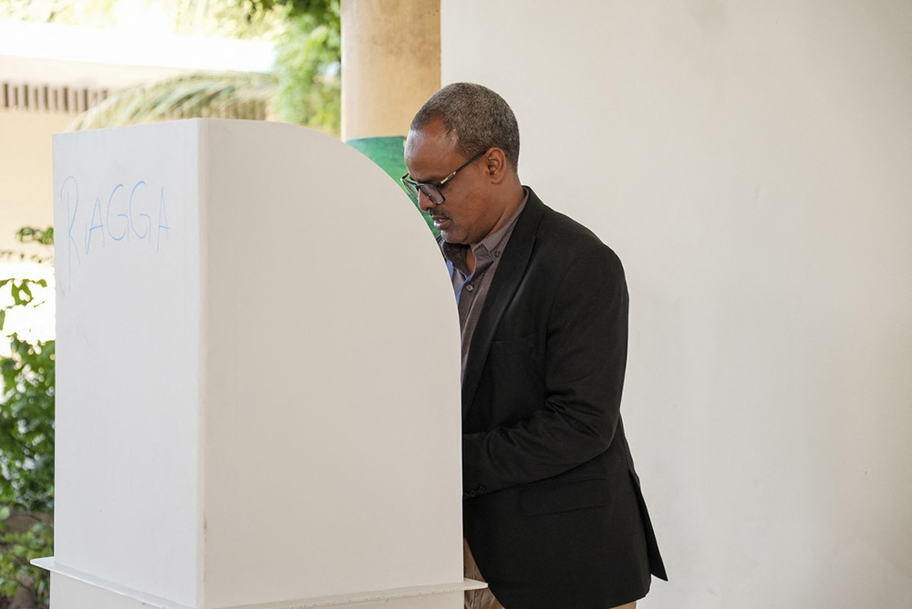 A voter marks his ballot paper in a voting booth during local council elections in Mogadishu on December 25, 2025. Somalia's capital, Mogadishu, heads to the polls on December 25, 2025 for local elections, the first time in 58 years, under a complete citywide lockdown amid security concerns. (Photo by Hassan Ali ELMI / AFP)