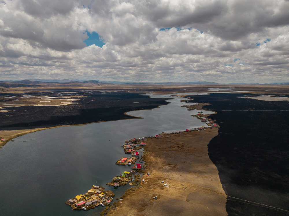 This aerial view shows a huge blackened area in the Lake Titicaca National Reserve near the floating islands of the Uros in Puno, Peru, on October 23, 2026, following a fire that ravaged around 400 hectares of totora reeds on October 21. (Photo by URIEL MONTEFUR / AFP)