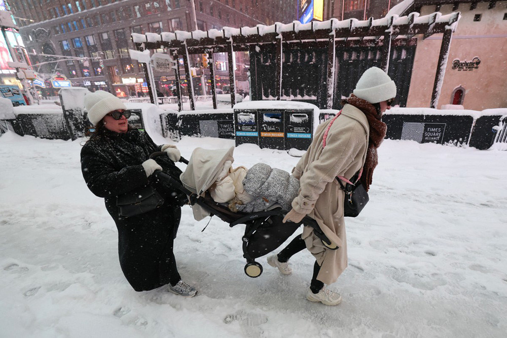  People carry a baby stroller during a winter storm in the Manhattan borough of New York City on February 23, 2026. (Photo by TIMOTHY A.CLARY / AFP)