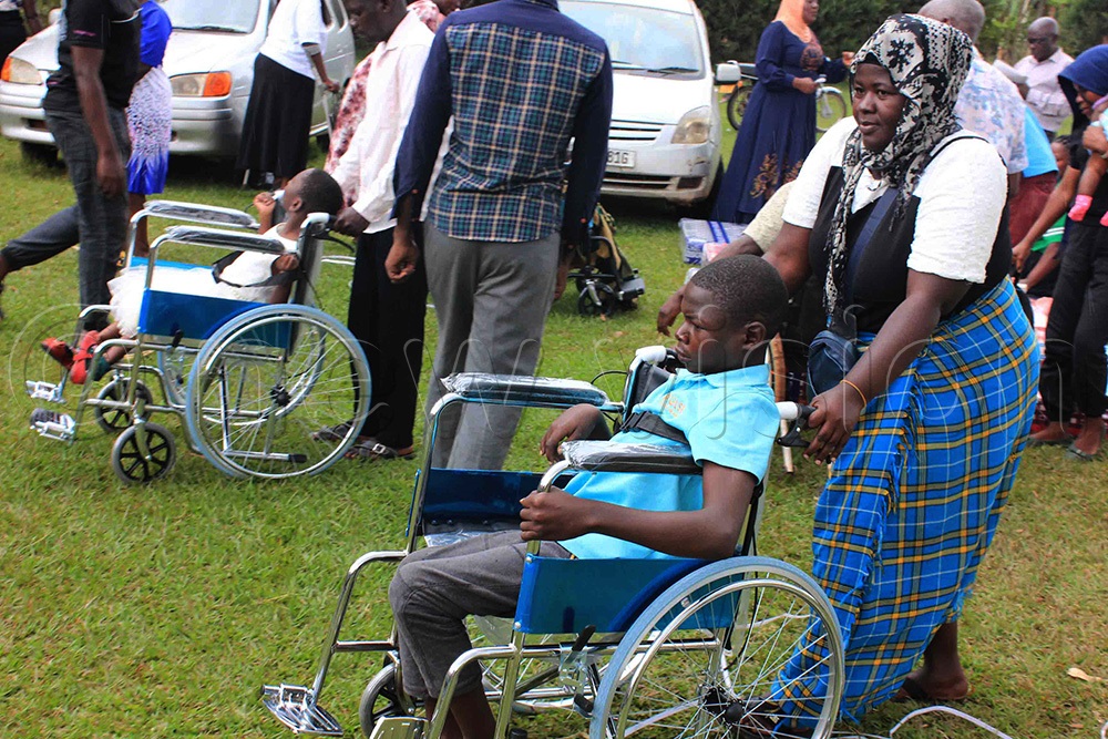 One of the parents pushing his son in a brand new donated wheelchair. (Photo by Henry Nsubuga)