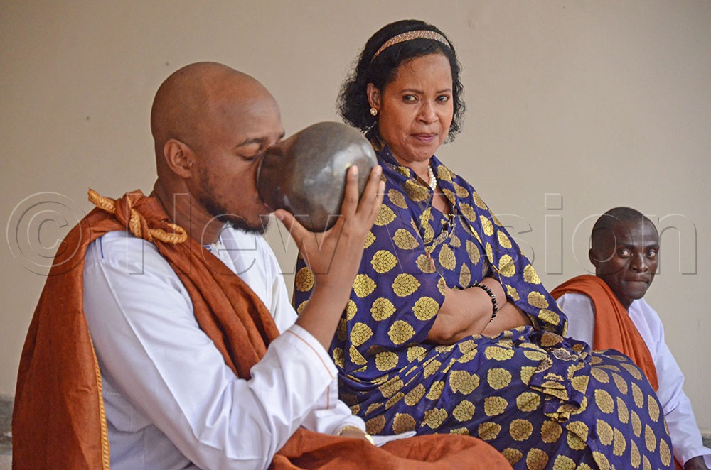 King Oyo drinking milk from a calabash as he performed some rituals. On the right is Queen Mother Best Kemigisa.