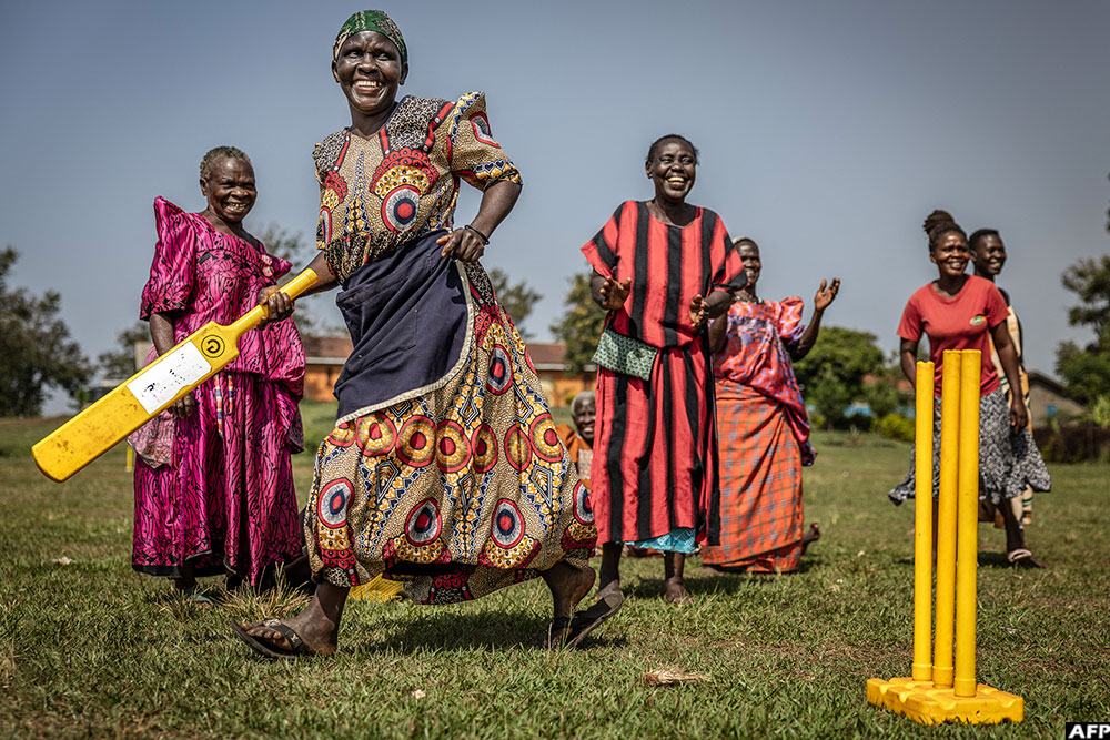 An elderly woman runs between the wickets as others react during a cricket and physical training session in Jinja.