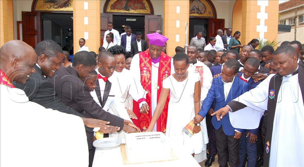 The headteacher of  Makerere College School ( MACOS),  Dr. Martin Muyingo (second-left), the Rev.  Dr. Richard  Mulindwa (left), Rev. Nsaale Kitayimbwa (sixth-left) and Archbishop Samuel Stephen Kaziimba Mugalu (wearing a purpel biretta) cutting cake with the students of MACOS during the confirmation service. 