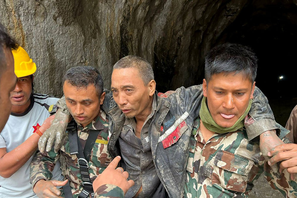 This handout photograph taken and released on September 5, 2026 via the Facebook page of Nepal Army shows security personnel carrying a Chinese national (2R) rescued from the Audit Tunnel 4 of the Upper Trishuli-1 Hydropower Project site in Nepal's Rasuwa district in the aftermath of flash floods. (Credit: AFP)