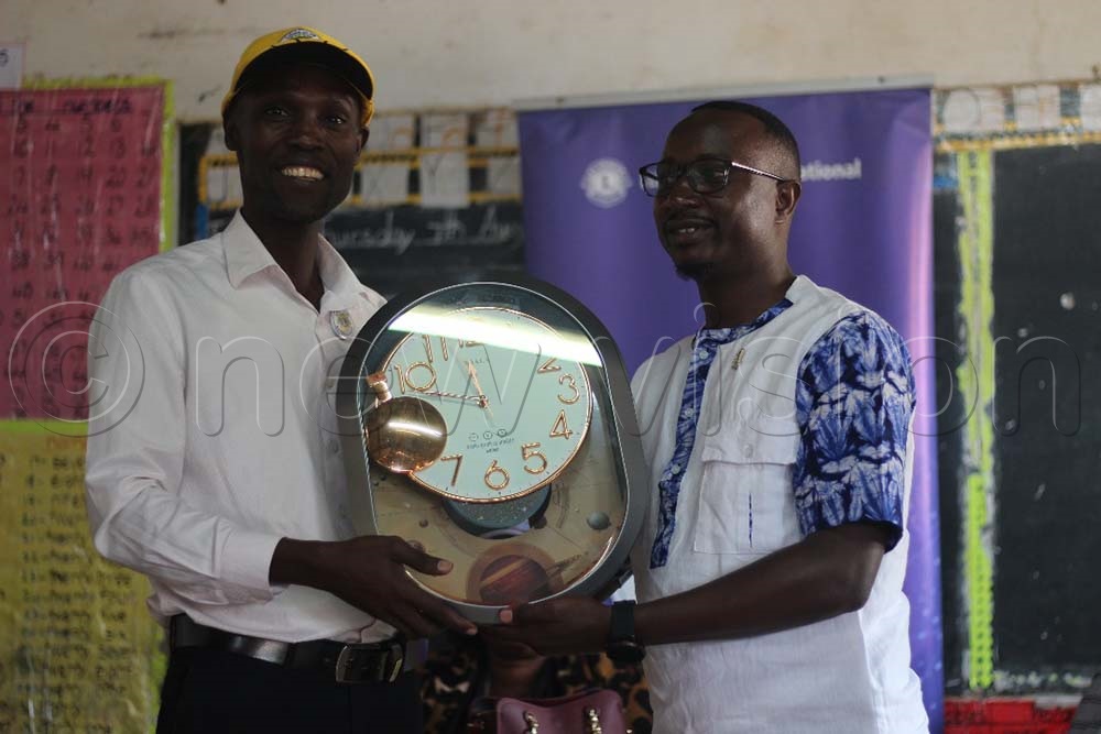 Lions Club President Ivan Sendege (R) hands over a clock to Moses Tukei, headteacher at Creative Infant Primary School, during their compassionate visit. (Credit: Richard Ategeka)