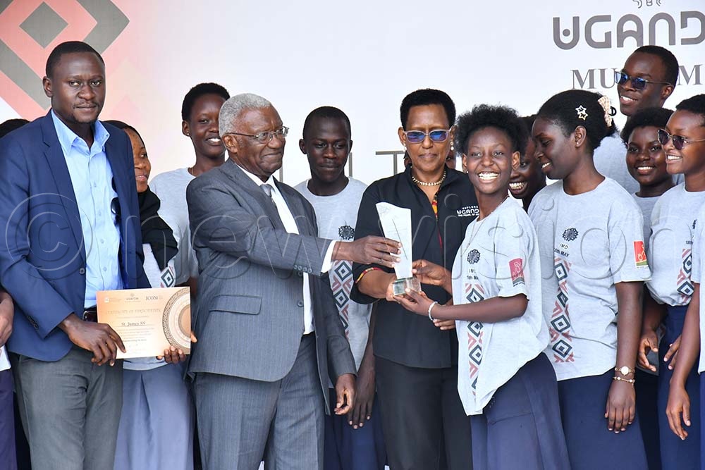 The Minister of Tourism, Wildlife and Antiquities, Col. (Rtd) Tom Butime (3rd L) and Doreen Katusiime (C) the permanent secretary of the Ministry of Tourism handing over a prize to students of St. James Secondary School after emerging winners in the secondary school quiz competition while at celebrations to mark the International Museums Day at the Jinja Rugby grounds on May 18th. (Credit: Donald Kiirya)