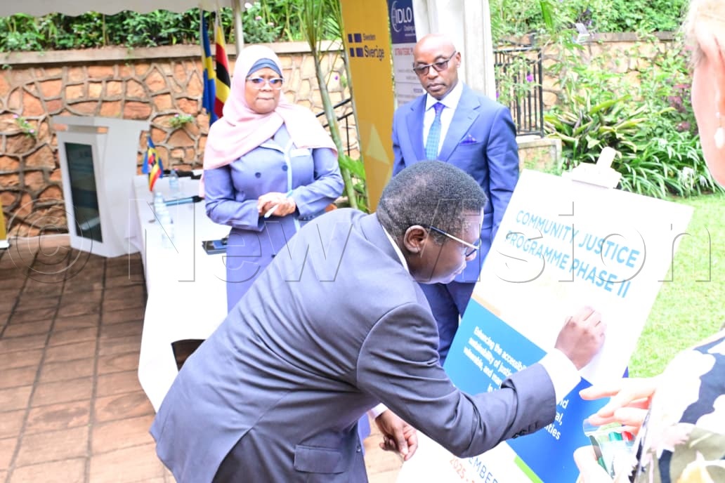 Minister for Justice and Constitutional Affairs, Norbert Mao, signing on the board.