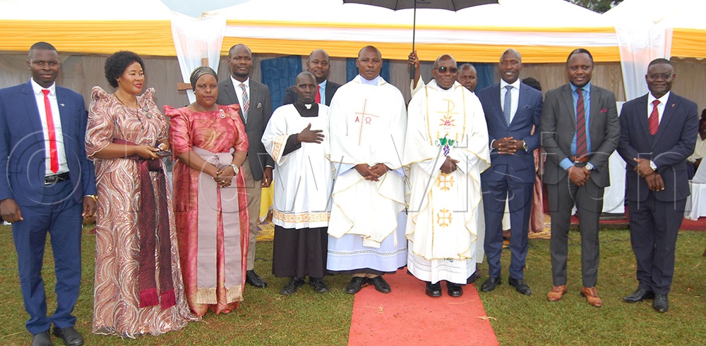 Msgr. Charles Kasibante (wearing glasses) shares a photo-moment with Fr. Denis Ssekamaanya (on his immediate right), Fr. Bernard Mpoza (wearing a surprice), Hon. Teddy Nambooze (second-left), Mpigi Town Council Mayor Faridah Ssempala (third-left), Hon. Robert Ssekitoleko (third-right), Hon. Hillary Kiyaga (second-right), Gabriel Kabonge (right), and some other guests during the celebrations. (Photo by Mathias Mazinga)