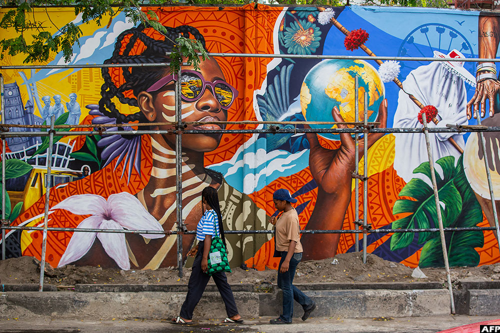 Pedestrians walk past a mural on Ozumba Mbadiwe Avenue. (AFP)