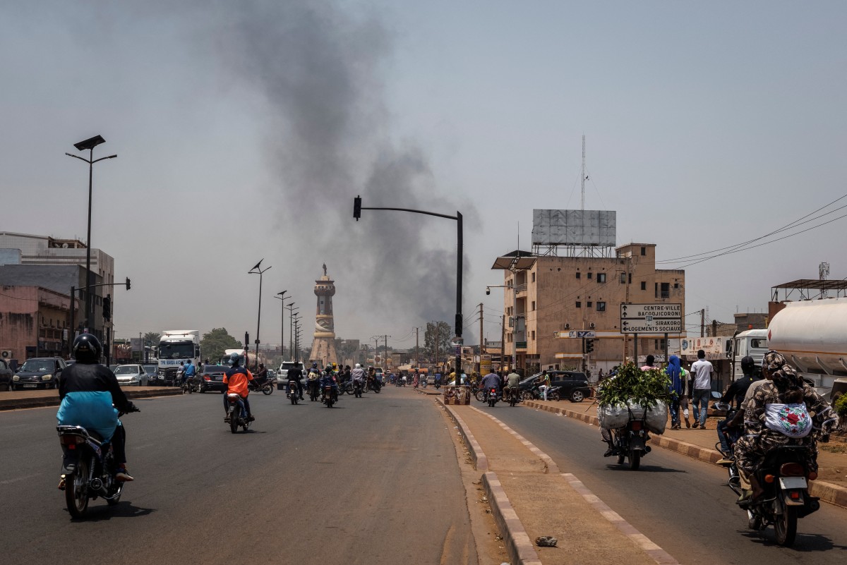 A column of black smoke rises above buildings as traffic passes the Africa Tower monument in Bamako on April 26, 2026. April 25, 2026's shock attacks, synchronised by Tuareg rebels of the Azawad Liberation Front (FLA) coalition and the jihadist Group for the Support of Islam and Muslims (JNIM), targeted several areas in the vast arid country. (AFP)