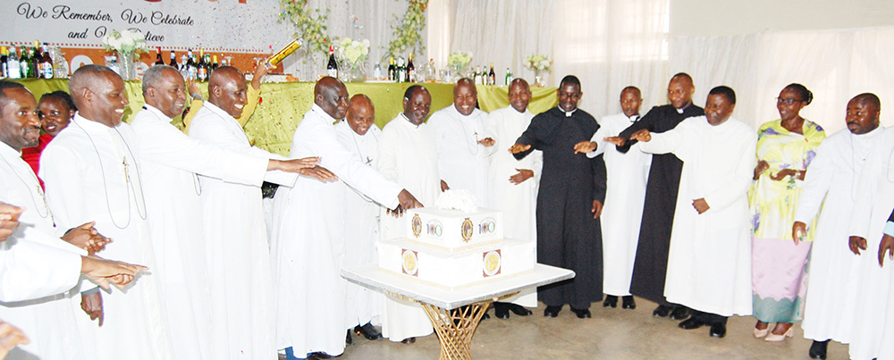 The Brothers of Christian Instruction led by Bro. Casio Aizire (fifth-left) and the Catholic priests, cutting cake in celebration of the 104th anniversary of St. Henry's College Kitovu and the centenary of the presence of their religious institute in Uganda. (Photo by Mathias Mazinga)