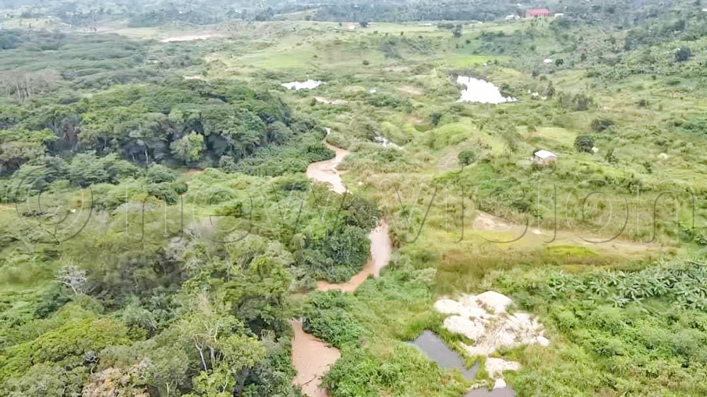 An aerial view of small mining pits (middle ground) next to Kasyoha-Kitomi Forest Reserve and the polluted River Buhindagi separating the forest and private land in Kyabakara sub-county, Rubirizi district. (Credit: Gerald Tenywa)