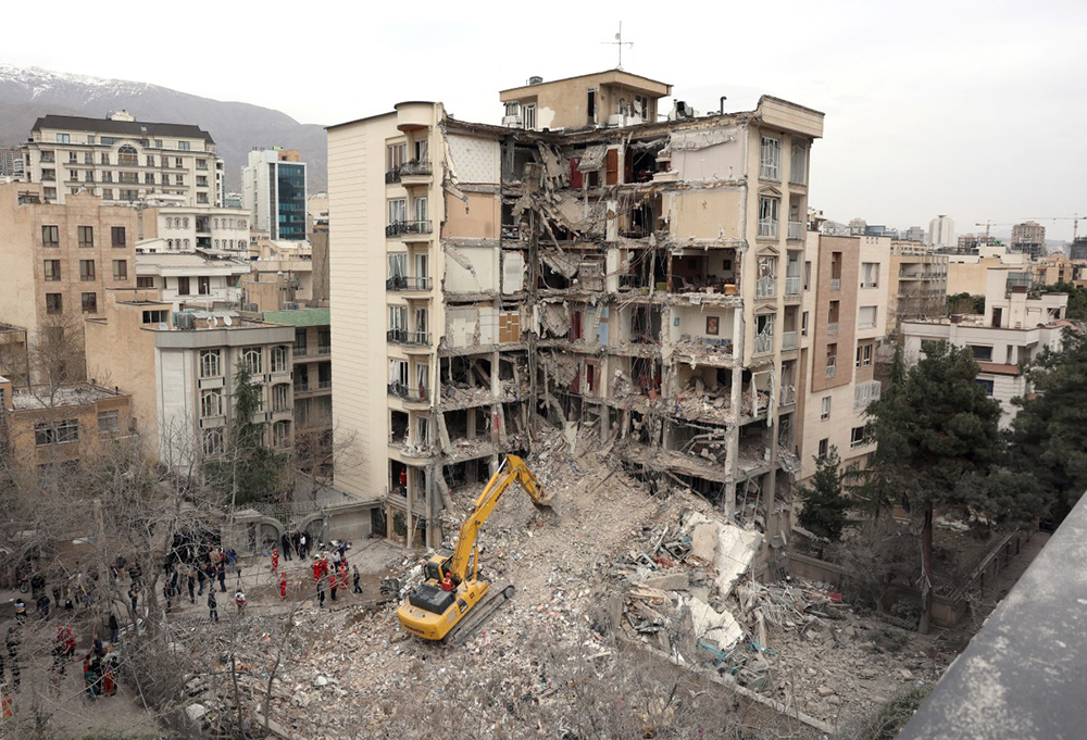 An excavator clears rubble from destroyed residential buildings in northern Tehran on March 23, 2026.