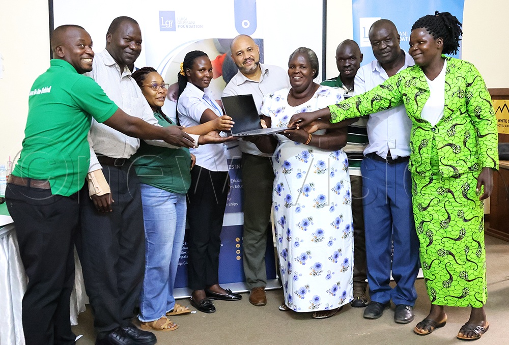 Officials from the Luigi Giussani Foundation and Oxfam hand over a laptop to Monicah Alimah Draleru, deputy head trainer at Inde Skills Development Centre in Madi Okollo, and staff. (Photo by Robert Ariaka)