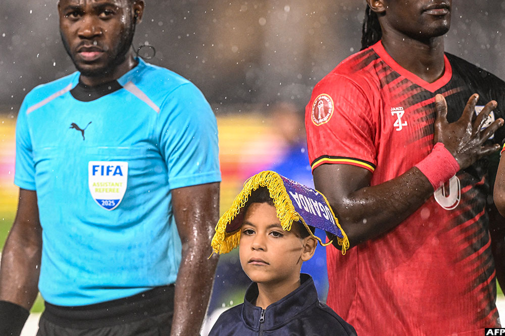 Uganda skipper Khalid Aucho protected this young mascot from the rain with the pennant of Uganda.
