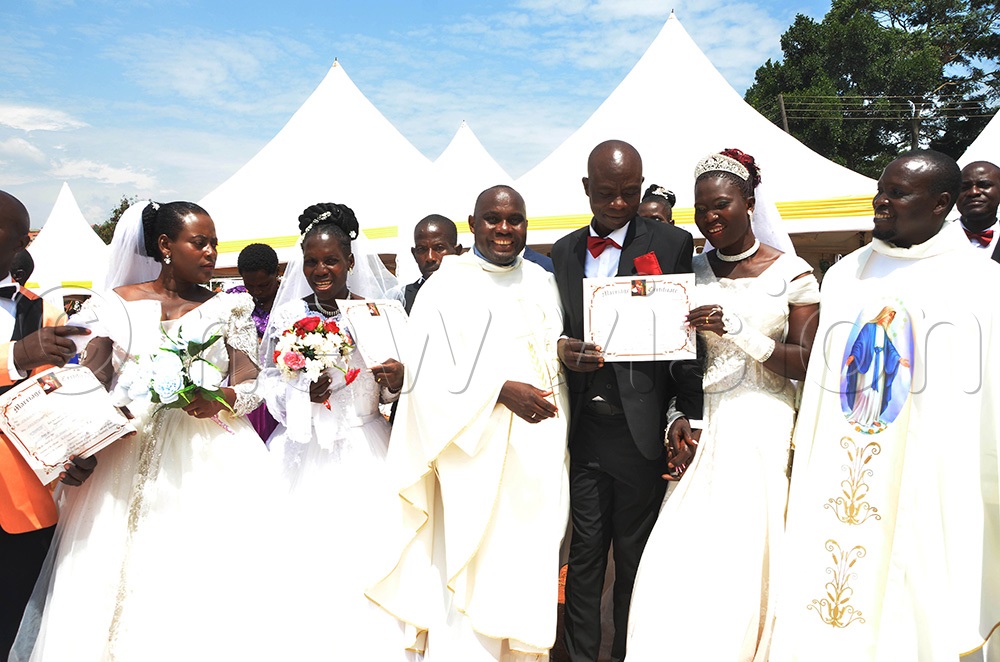 The Dean of Entebbe Deanery, Fr Basil Fredrick Mirundi (left) and Fr Remigius Kasibante with some of the couples after wedding them at St Padre-Pio Catholic Parish Kabulamuliro. (Photo by Juliet Anna Lukwago)