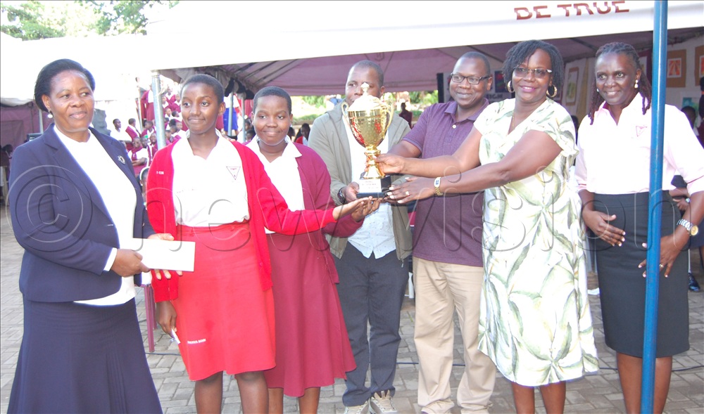 The  Tricona  students from the Chemistry Department (wearing the school's uniform) share a photo-moment with the headteacher Immaculate Lwanga (left), her deputy Lady Alex Kigozi (right) and some of their teachers after being declared as the champions of the school's curriculum exhibition of 2026. 