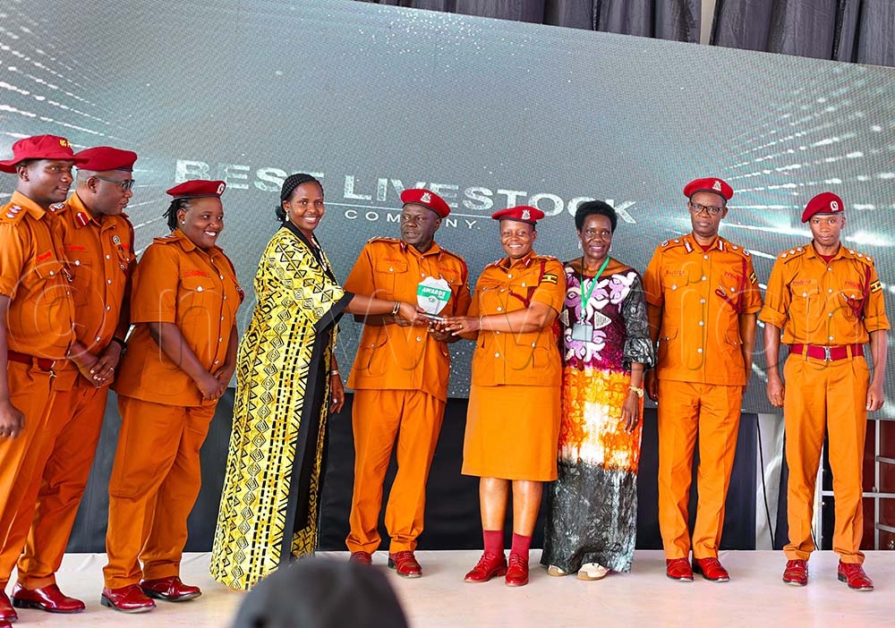 Desire Muhooza, the Minister of State for Agriculture presents an award to prison officers in recognition of their exceptional exhibition at the National Agricultural show in Jinja city recently. (Credit: Petride Mudoola)