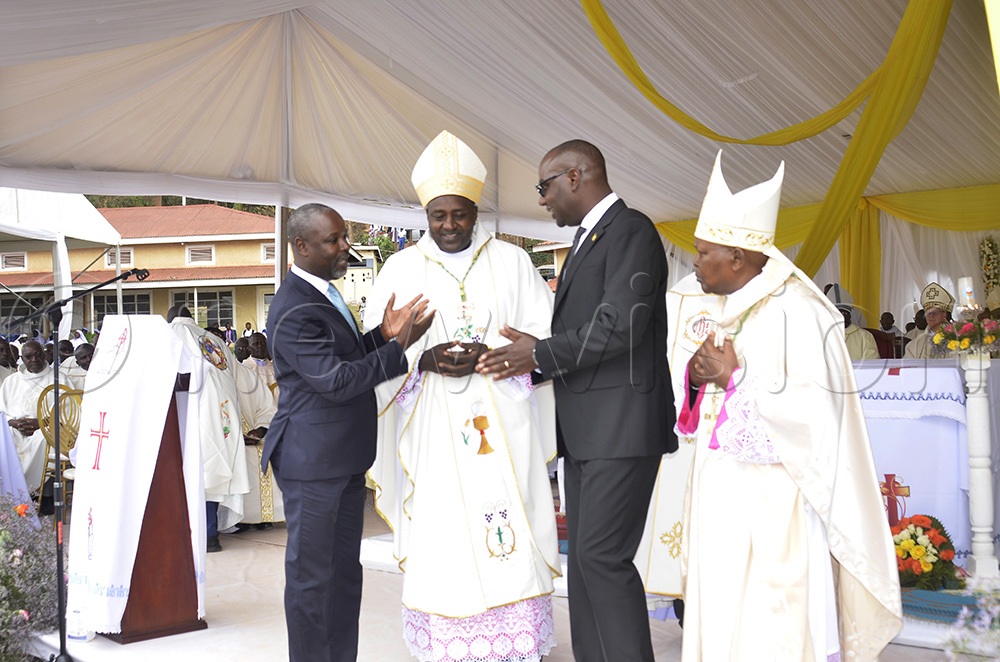 (L-R) Deputy Speaker, Thomas Tayebwa and Minister for Finance, Henry Musasizi, chat with the newly ordained Bishop of Kabale Catholic Diocese, Bonaventure Bosco Katusiime Gubazire (MAF), as the retired Bishop of Kabale, Callistas Rubaramira, looks on. (Photo by Juliet Anna Lukwago)