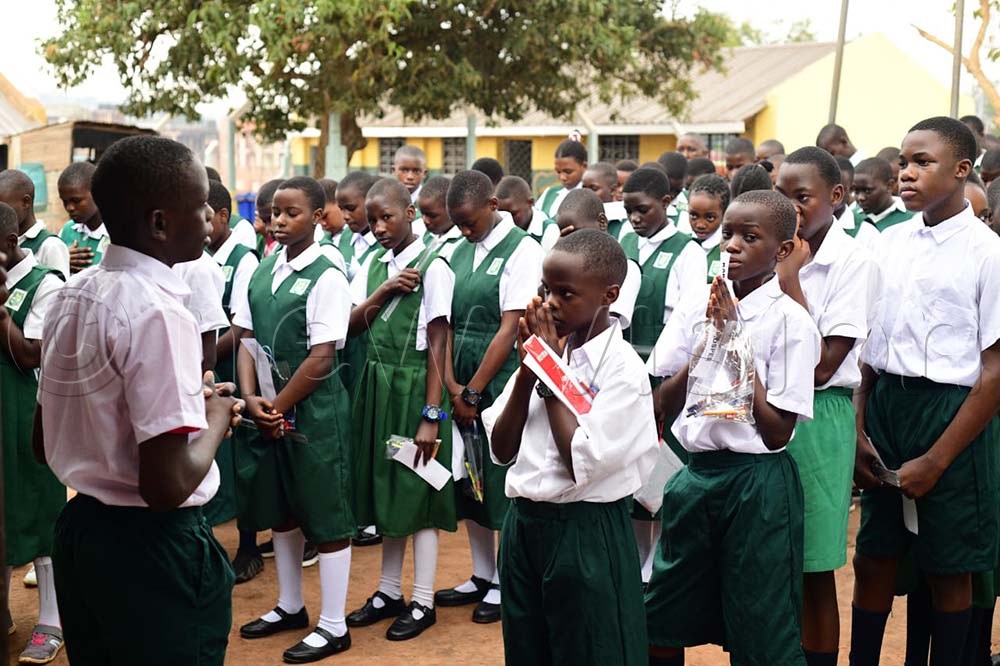 A pupil leads colleagues in prayers before entering the examination room for their first PLE Mathematics exam. (Credit: Maria Wamala)