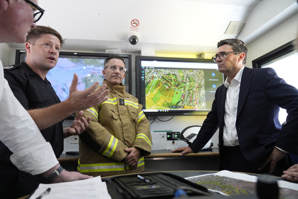 Britain's Prime Minister Andy Burnham speak with emergency responders at the West Midlands Fire Service incident command unit, during a series of wildfires, in Stourbridge, central England on August 14, 2026. Firefighters continued Friday to extinguish wildfires that began on August 13, tearing through several homes, with residents evacuated and "extensive" damage reported. 