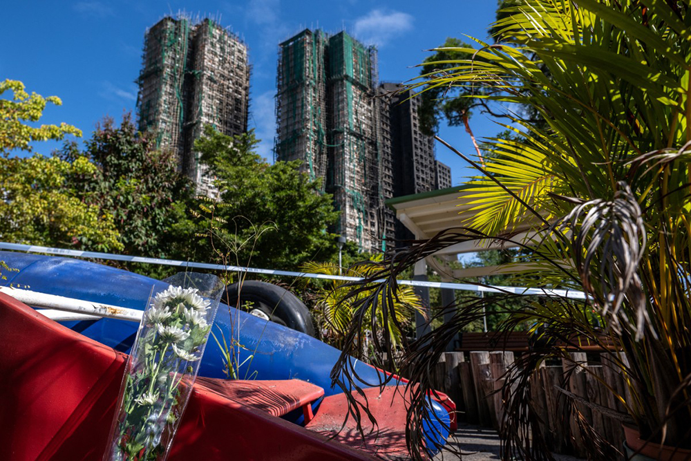 Flowers are seen outside the Wang Fuk Court (back) in the aftermath of the deadly November 26 fire in Hong Kong's Tai Po district on November 29, 2025. 