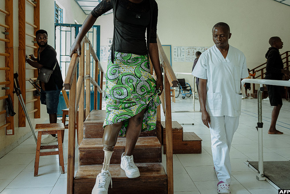 A patient tests her new prosthesis, going up and down therapeutic stairs as a technician observes, at the Shirika la Umoja centre